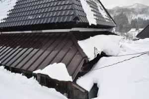 雪に埋まったトタンをかぶせた茅葺き民家